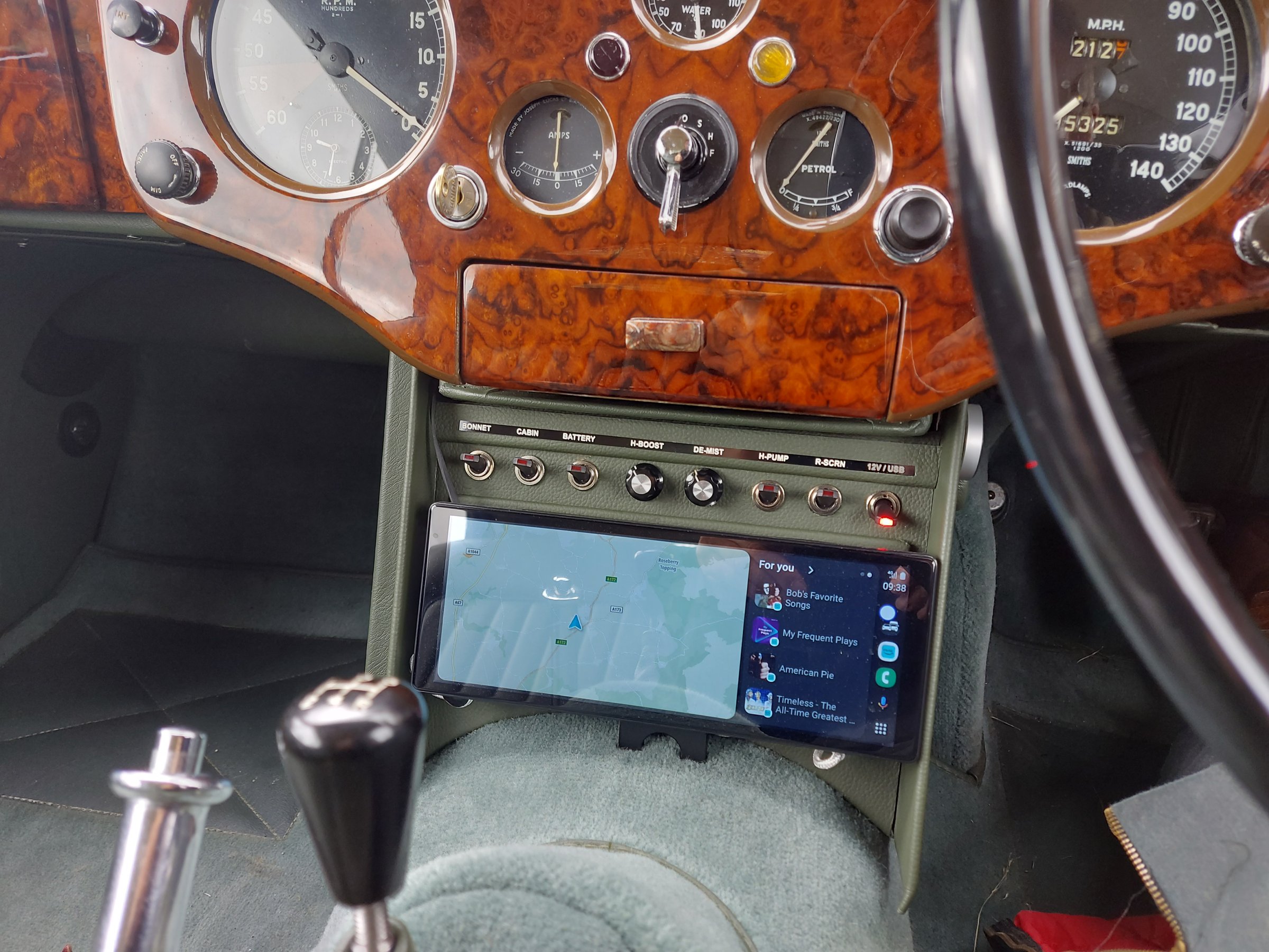 The restored dashboard and centre console of an XK140, with a labelled row of switches