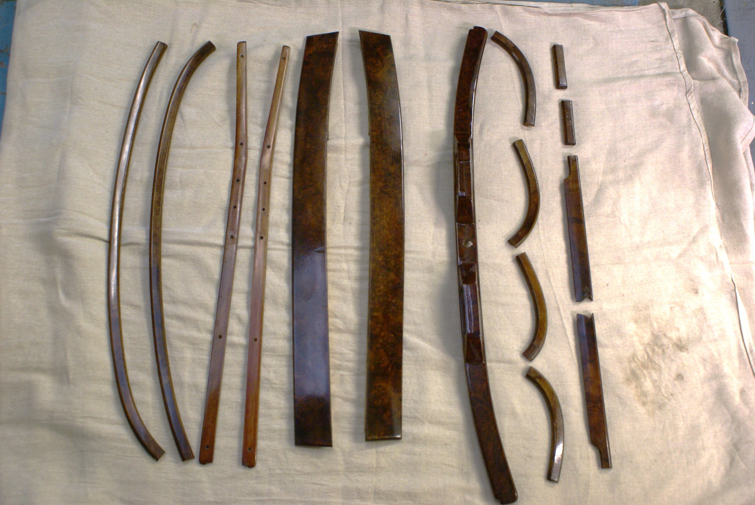Burr walnut trim pieces laid out on a cloth — window cappings, dash rails and curved sections