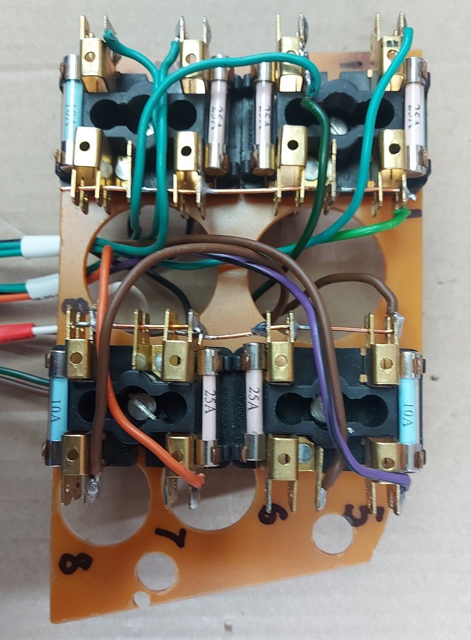 A fuse board with eight fuses and coloured wiring, numbered by hand