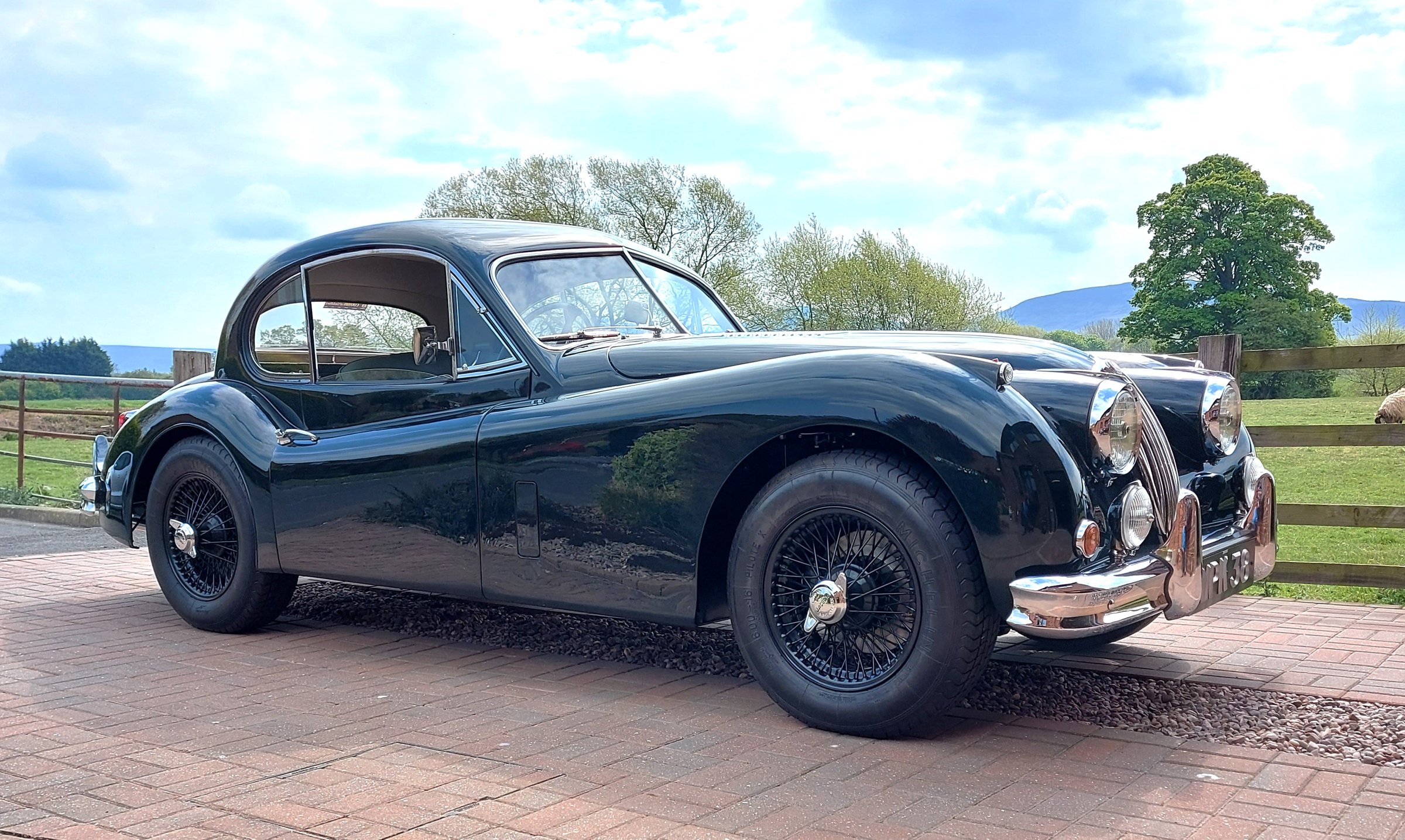 A dark green XK140 fixed head coupe from the front three-quarter